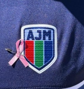 Detalle del escudo del Club Alianza Jesús María con un lazo rosa colocado en el pecho de una jugadora, símbolo de la campaña de concientización sobre el cáncer de mama.